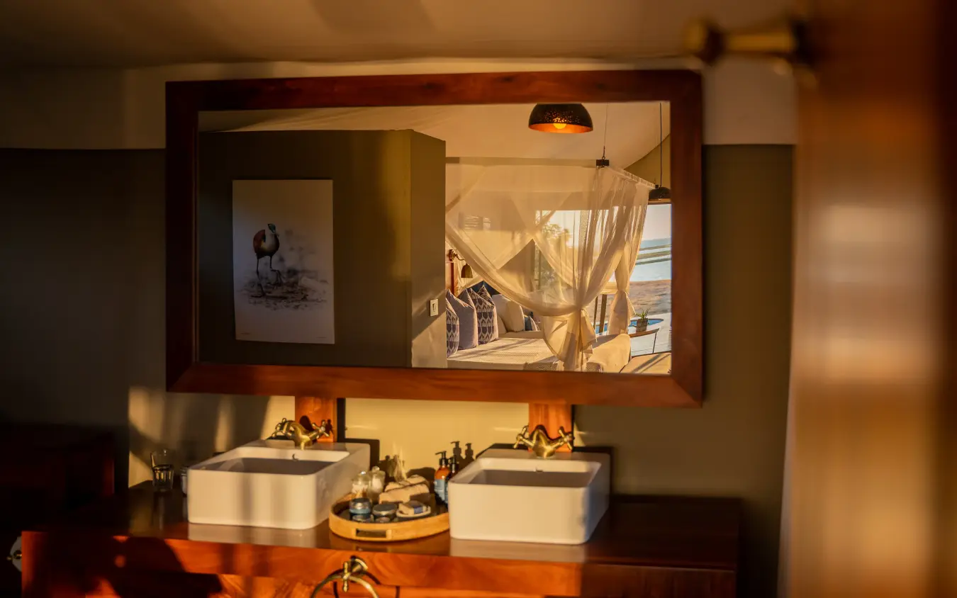 Luxury bathroom with dual vessel sinks and large mirror overlooking savanna, Fothergill Island, Matusadona National Park, Zimbabwe