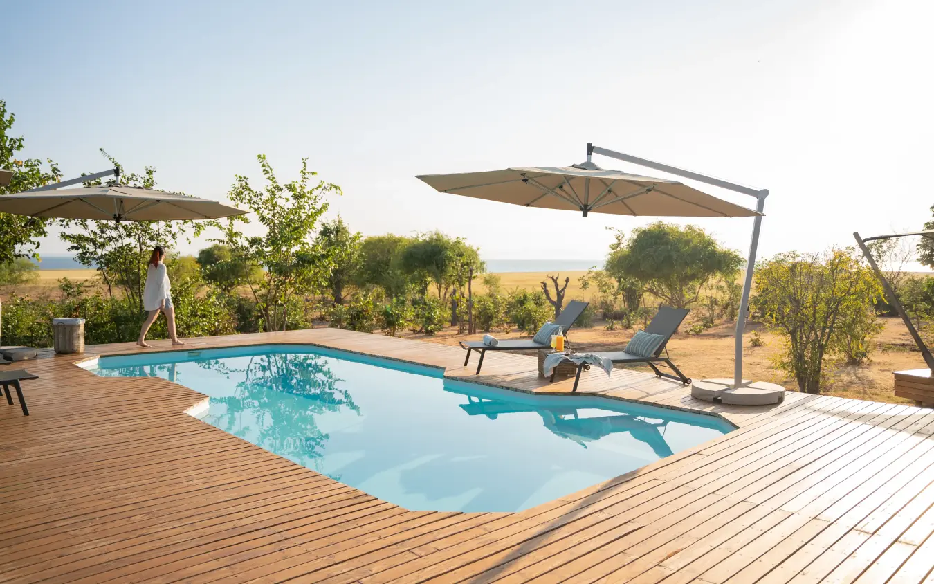 Swimming pool with loungers and umbrellas overlooking savanna landscape, Fothergill Island, Matusadona National Park, Zimbabwe