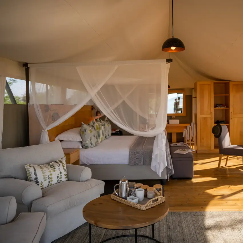 Luxury safari tent interior with canopy bed and savanna views through windows, Fothergill Island, Matusadona National Park, Zimbabwe