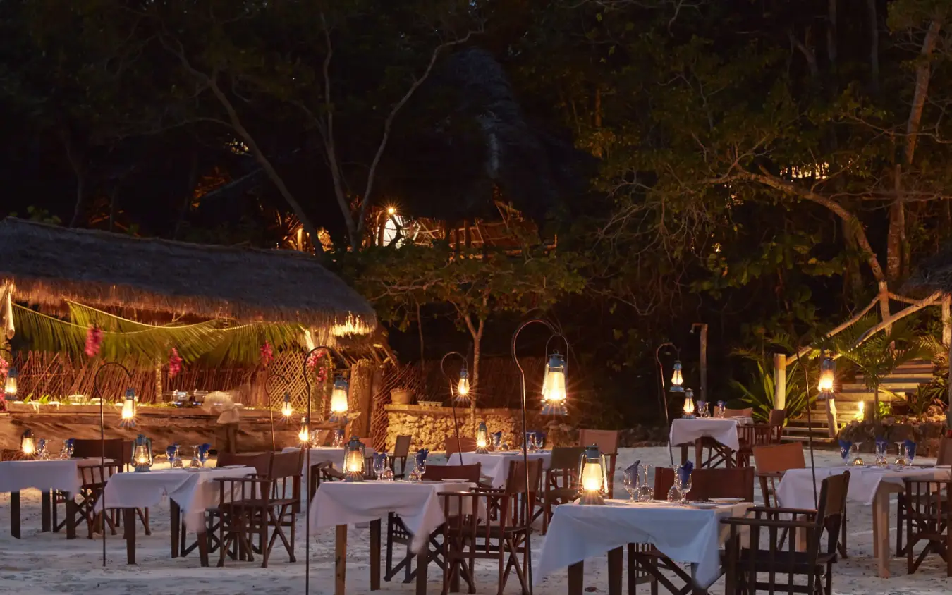 Beach dining setup with tables, chairs, and lantern lighting, Fundu Lagoon, Zanzibar & Pemba, Tanzania
