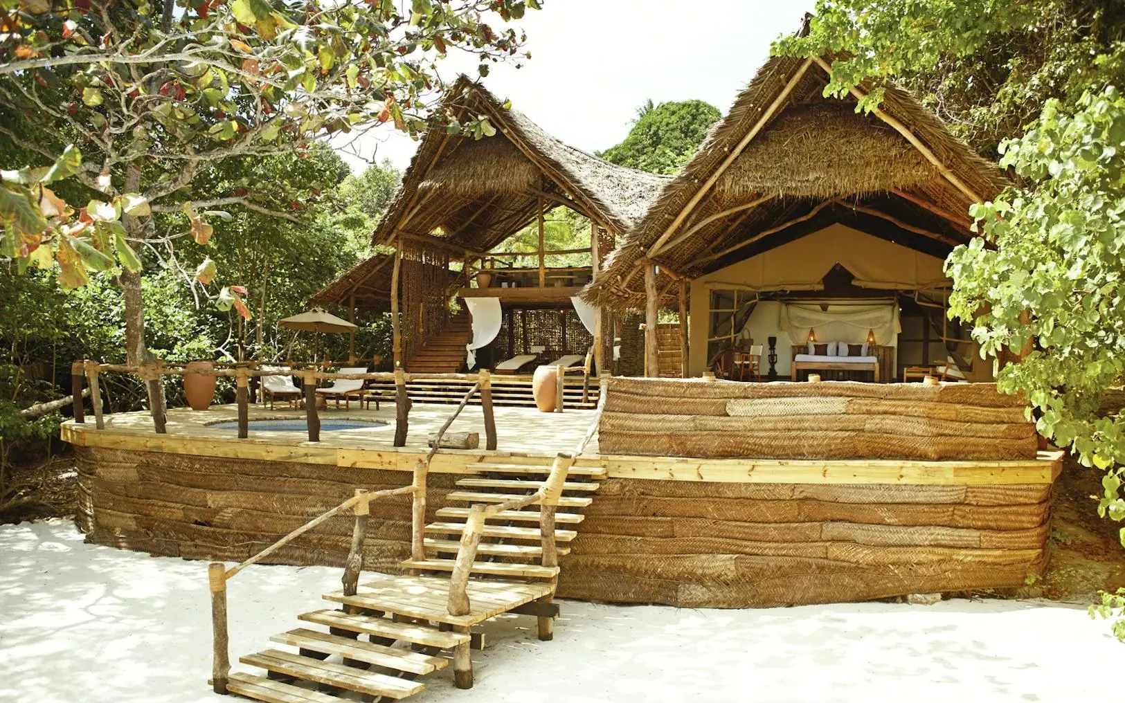 Thatched roof guest bungalows with wooden deck and stairs, Fundu Lagoon, Zanzibar & Pemba, Tanzania