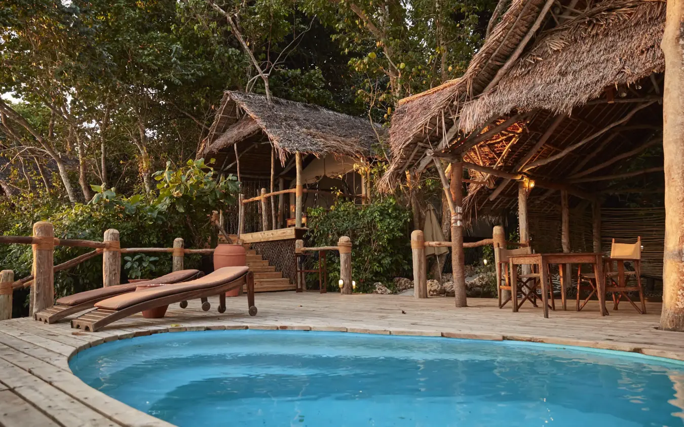 Swimming pool on wooden deck with thatched bungalows, Fundu Lagoon, Zanzibar & Pemba, Tanzania