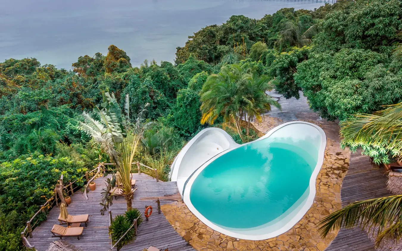 Turquoise swimming pool surrounded by wooden deck and tropical vegetation, Fundu Lagoon, Zanzibar & Pemba, Tanzania