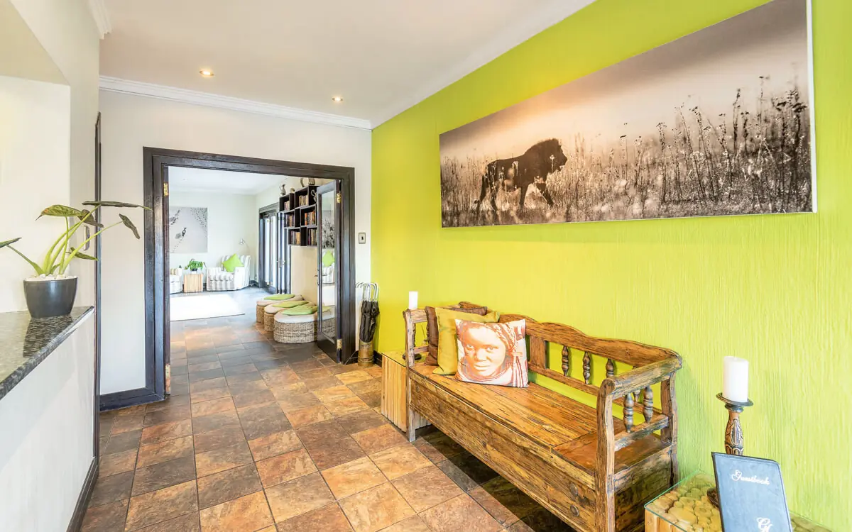 Bright green hallway with wooden bench and wildlife artwork, Galton House, Windhoek, Namibia