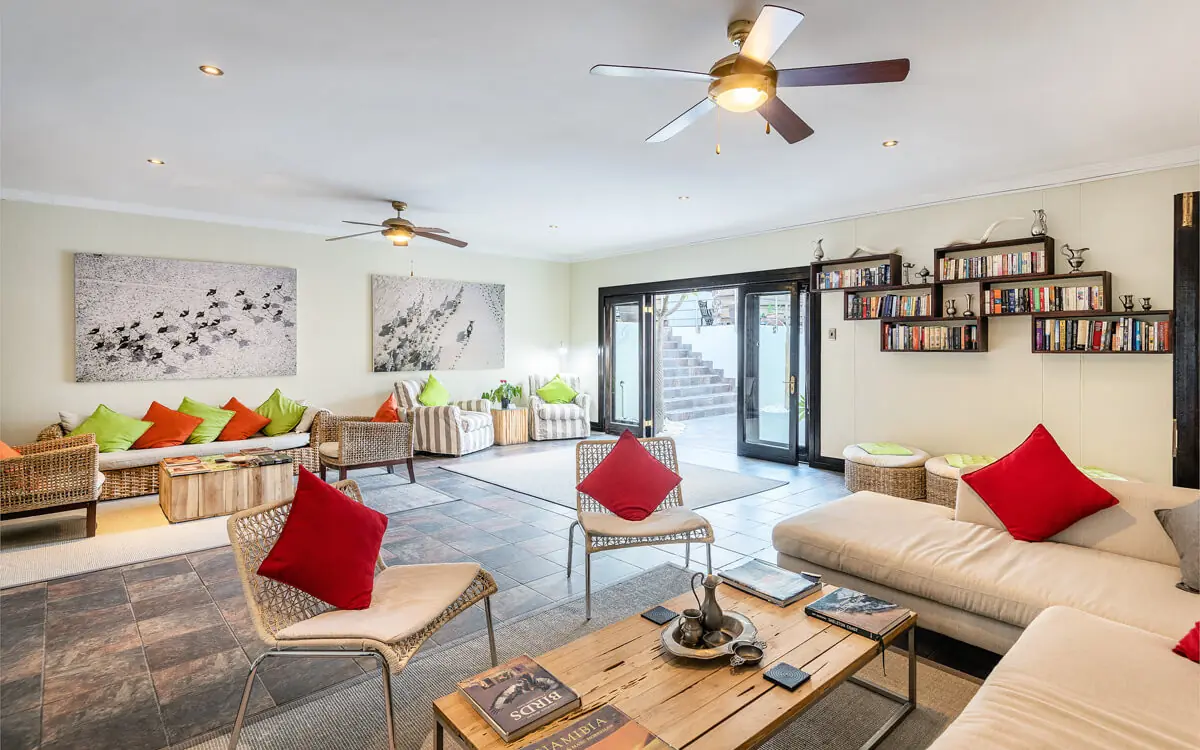 Spacious lounge with red cushions and ceiling fans, Galton House, Windhoek, Namibia