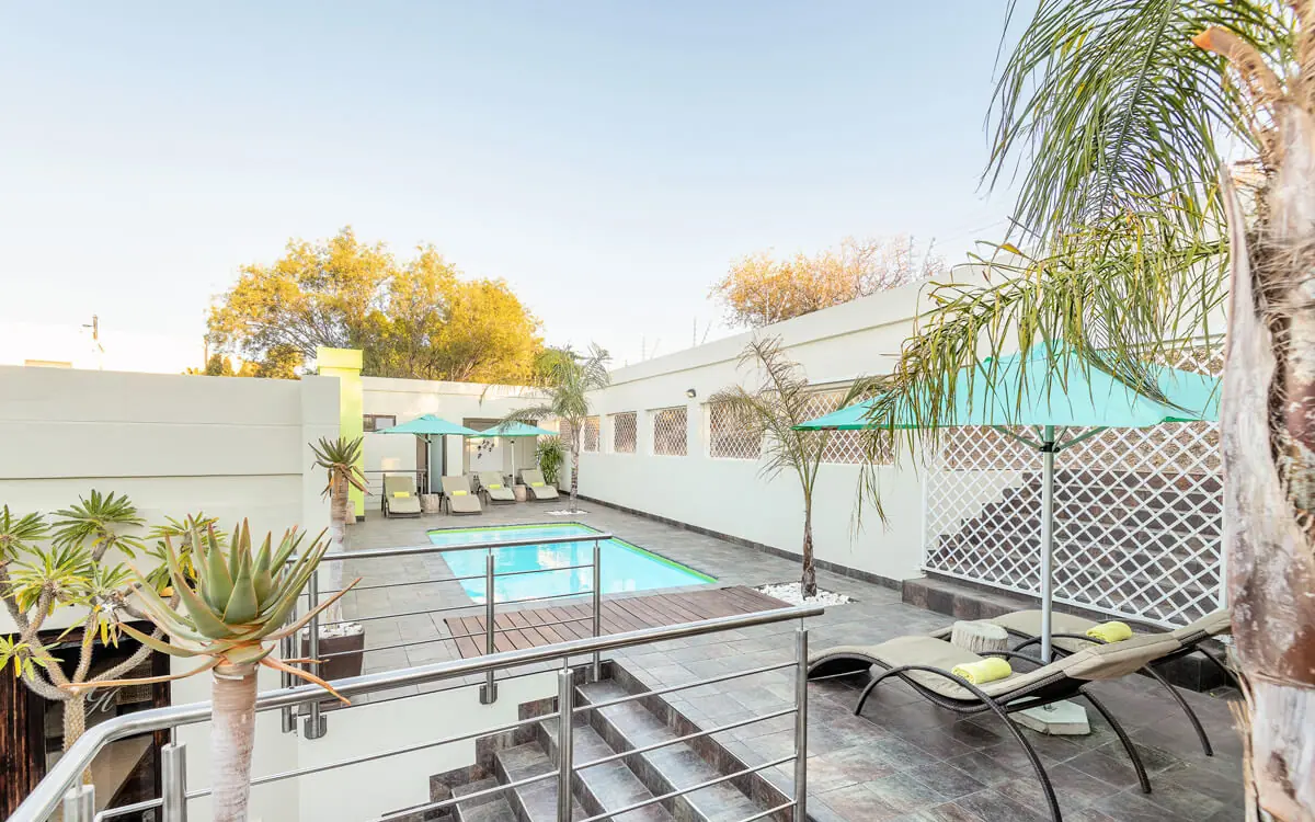 Swimming pool with lounge chairs and palm trees, Galton House, Windhoek, Namibia