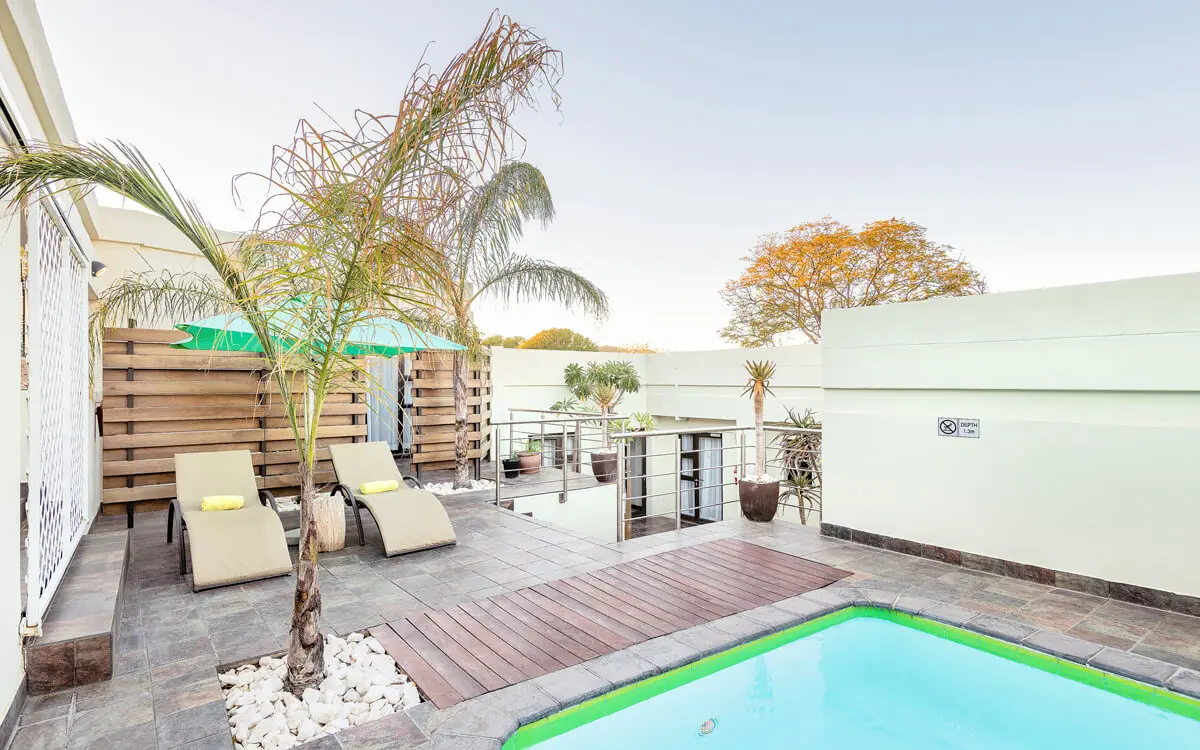 Rooftop pool area with loungers and palm trees, Galton House, Windhoek, Namibia