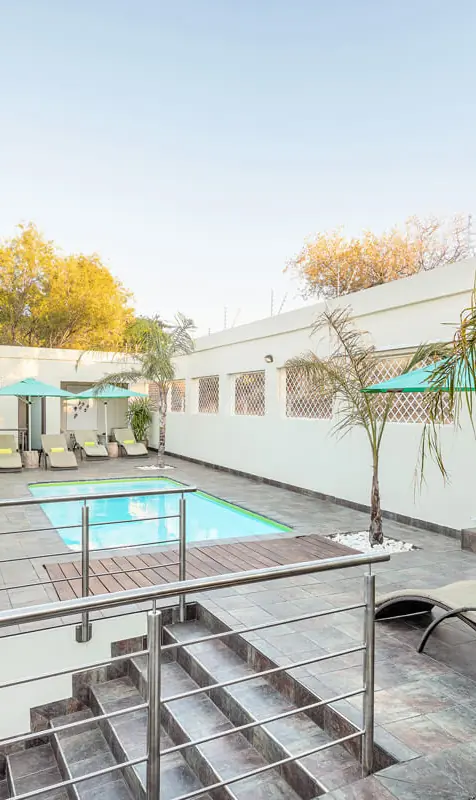 Swimming pool with lounge chairs and palm trees, Galton House, Windhoek, Namibia