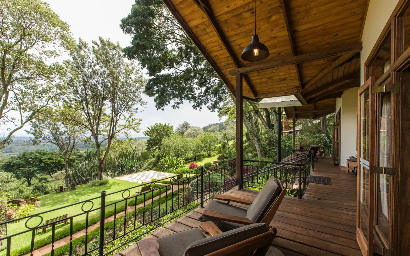 Wooden deck with lounge chairs overlooking green valley landscape, Gibb’s Farm, Ngorongoro Crater, Tanzania