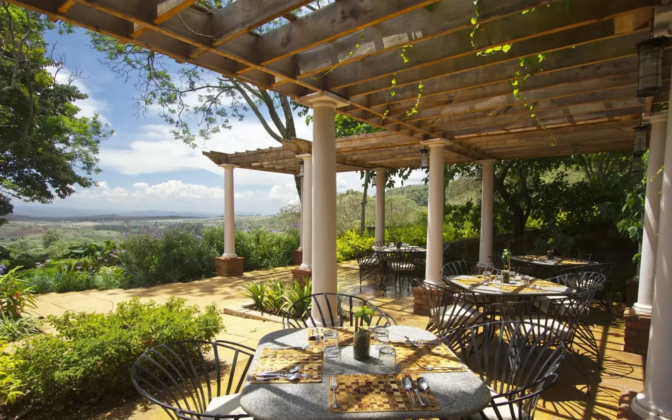 Covered terrace with dining tables overlooking valley landscape, Gibb’s Farm, Ngorongoro Crater, Tanzania