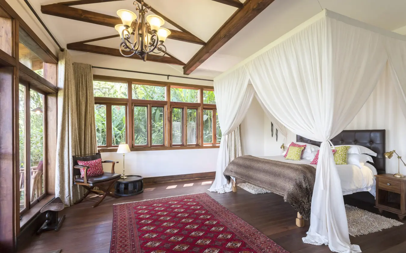 Spacious bedroom with four-poster bed and large windows, Gibb’s Farm, Ngorongoro Crater, Tanzania