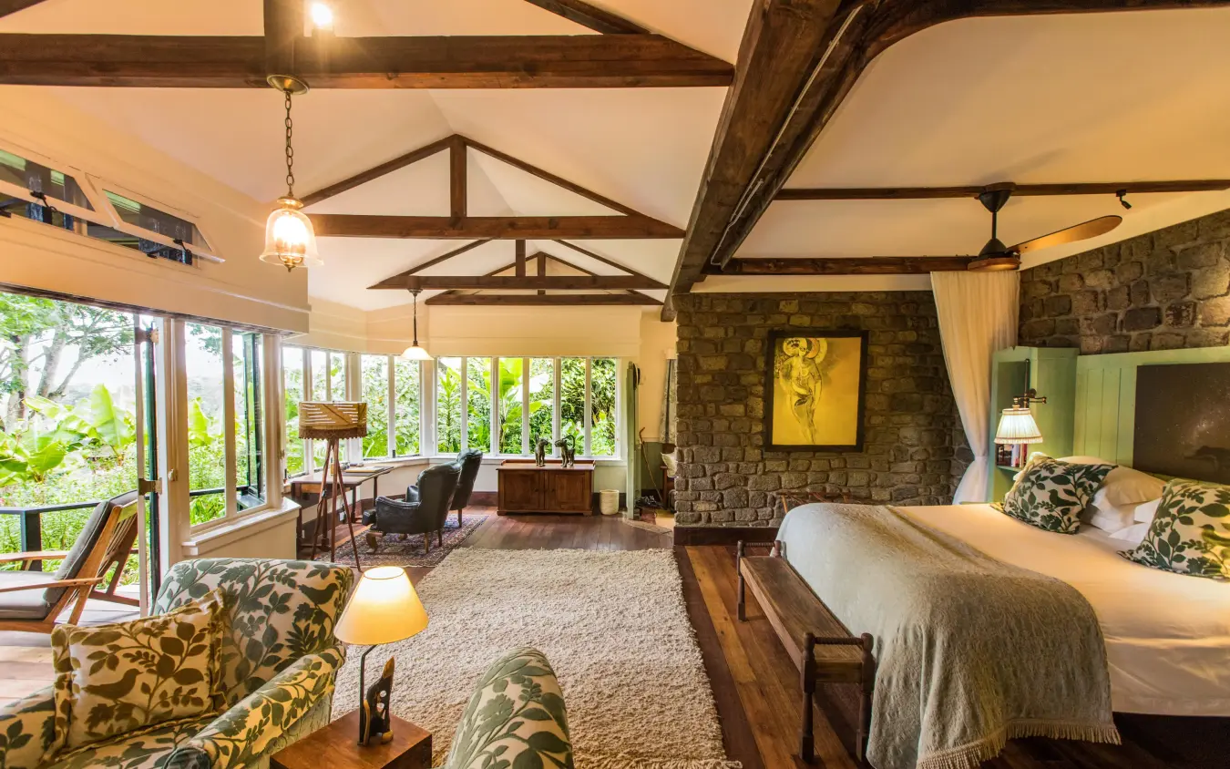 Spacious bedroom with exposed beam ceiling and stone fireplace, Gibb’s Farm, Ngorongoro Crater, Tanzania