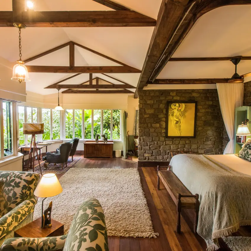 Spacious bedroom with exposed beam ceiling and stone fireplace, Gibb’s Farm, Ngorongoro Crater, Tanzania