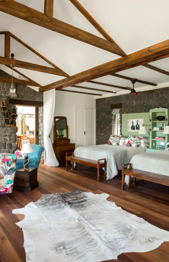 Spacious bedroom with exposed wooden beams and twin beds, Gibb’s Farm, Ngorongoro Crater, Tanzania