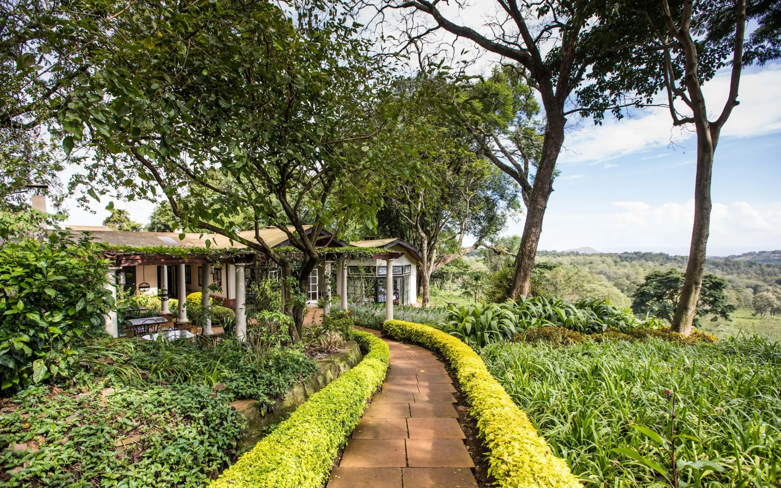 Manicured garden pathway leading to colonial-style lodge building, Gibb’s Farm, Ngorongoro Crater, Tanzania