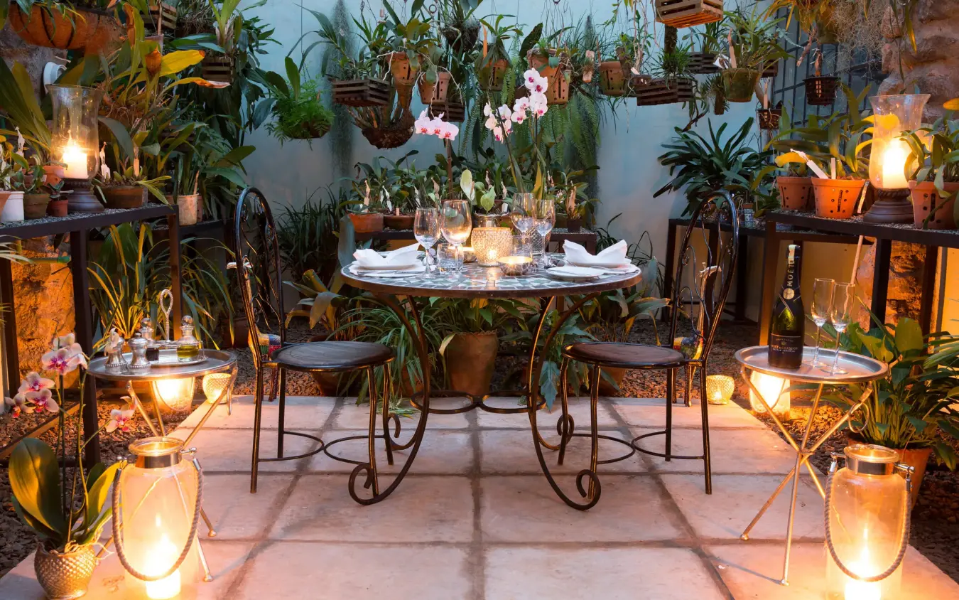 Intimate outdoor dining setup surrounded by potted plants and lanterns, Giraffe Manor, Nairobi, Kenya