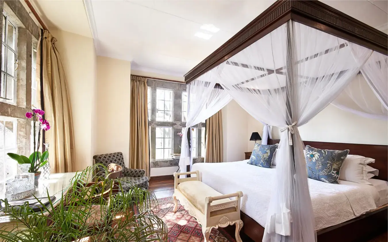 Elegant bedroom with four-poster canopy bed and seating area, Giraffe Manor, Nairobi, Kenya