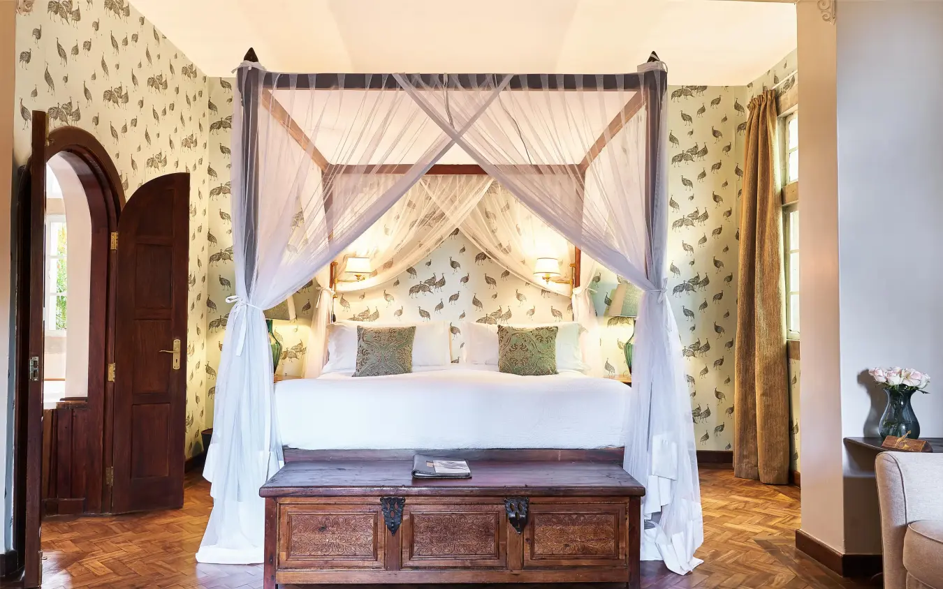 Canopy bed with sheer white drapes in bedroom, Giraffe Manor, Nairobi, Kenya