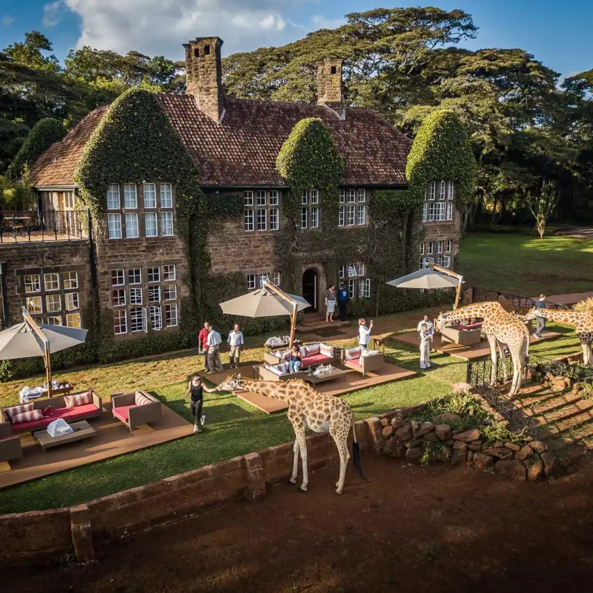 Historic manor house with guests and giraffes on manicured grounds, Giraffe Manor, Nairobi, Kenya
