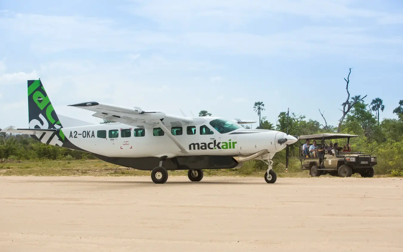 Cessna aircraft parked on airstrip with ground crew, Gomoti Plains, The Okavango Delta, Botswana
