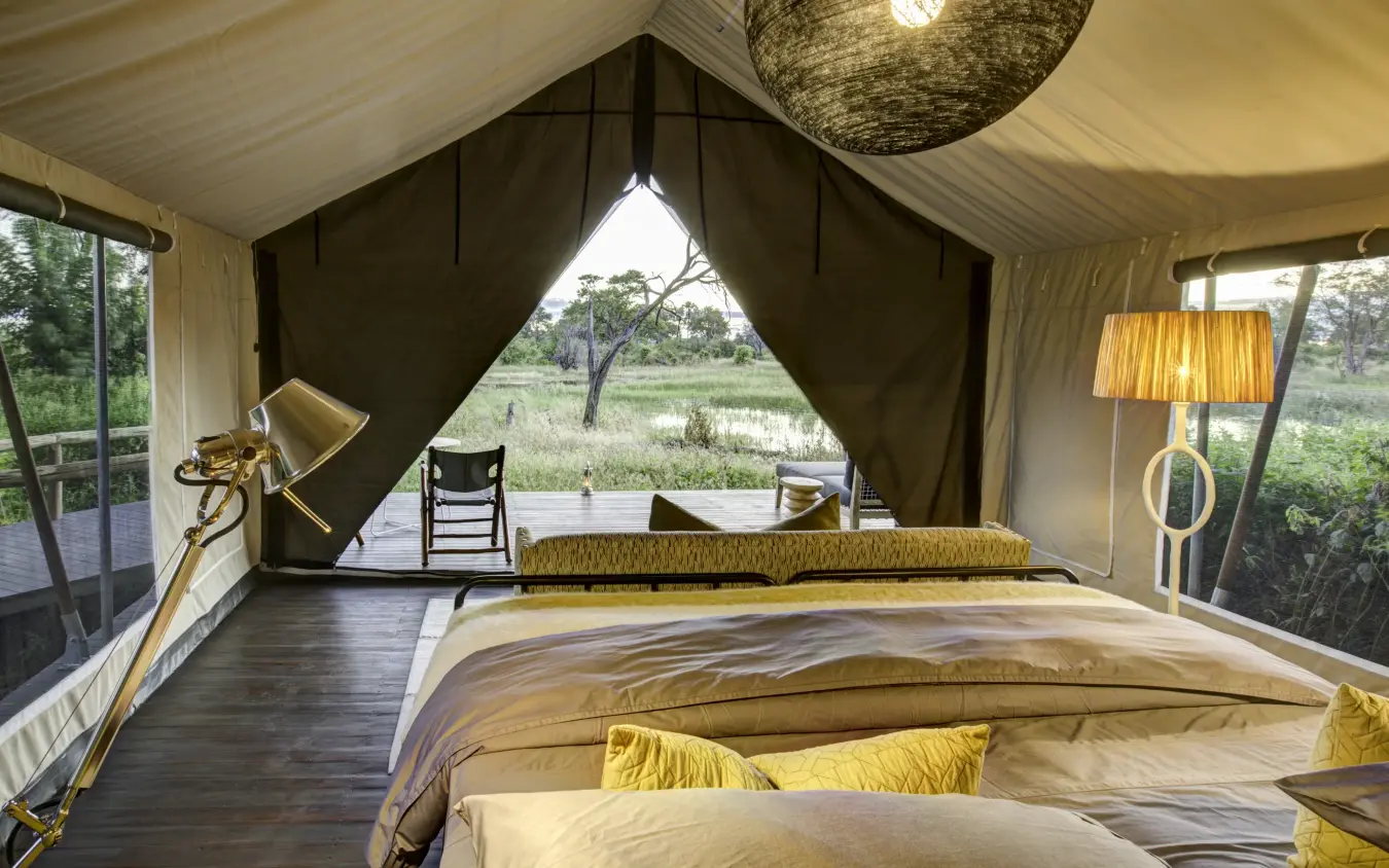 Luxury safari tent bedroom with canvas walls and savanna views, Gomoti Plains, The Okavango Delta, Botswana