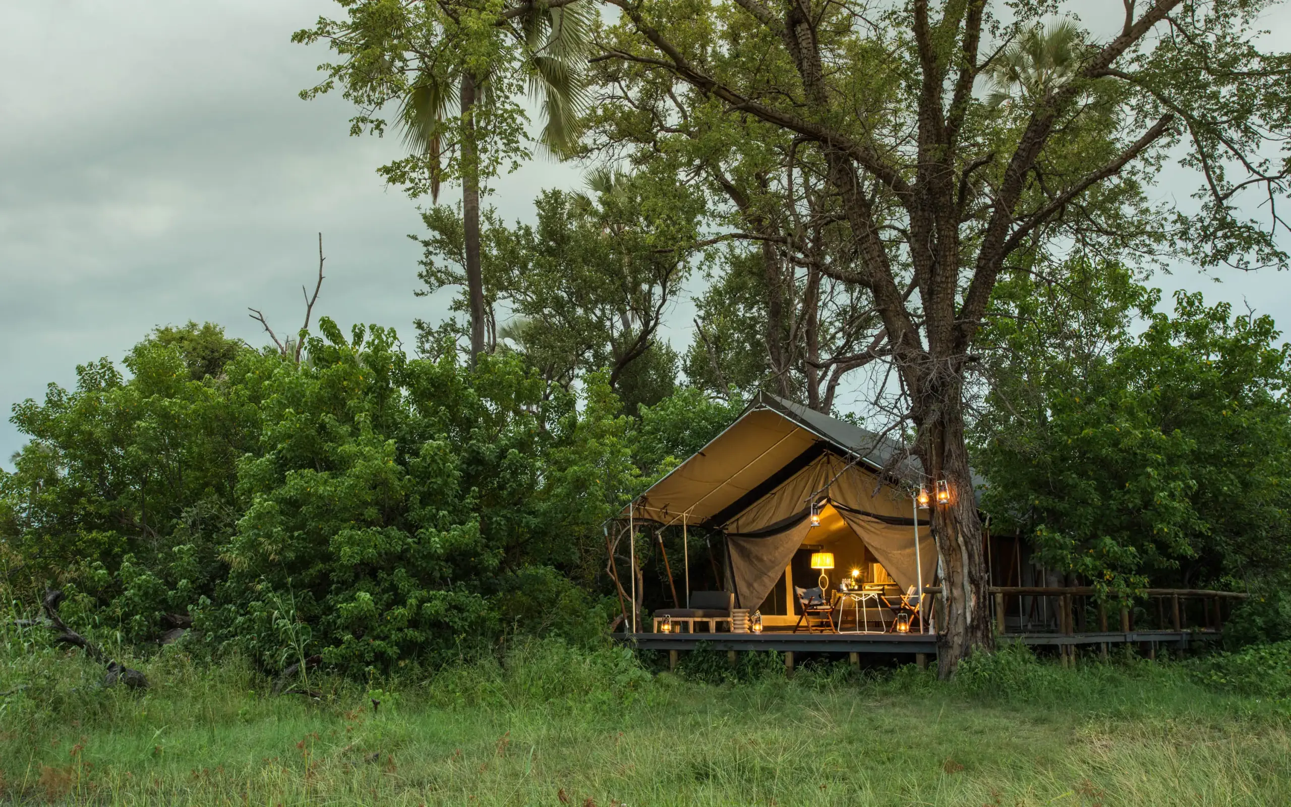 Safari tent accommodation with warm interior lighting at dusk, Gomoti Plains, The Okavango Delta, Botswana