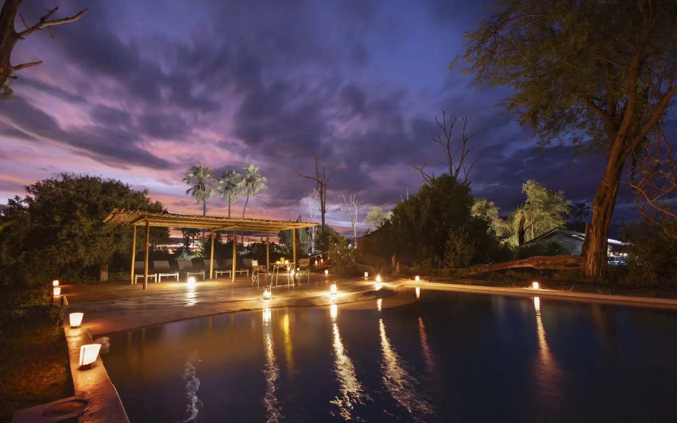 Illuminated pool deck at dusk with dining pavilion, Gomoti Plains, The Okavango Delta, Botswana