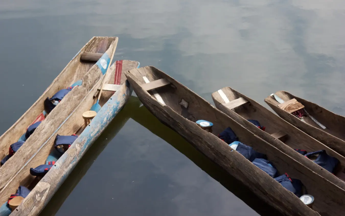 Wooden boats moored in calm water with blue fabric covers