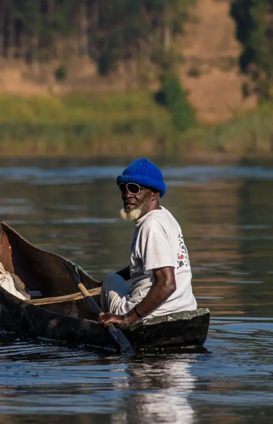 Man in boat on river with forested banks in background, Lake Kivu, Rwanda