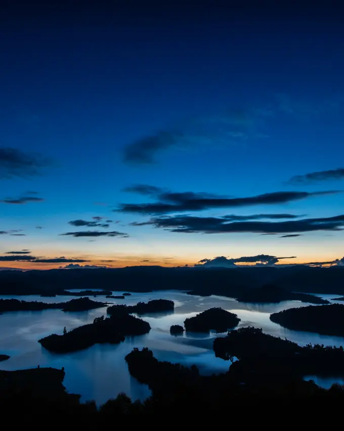 Silhouetted forested islands dotting lake at twilight with blue sky, Lake Kivu, Rwanda