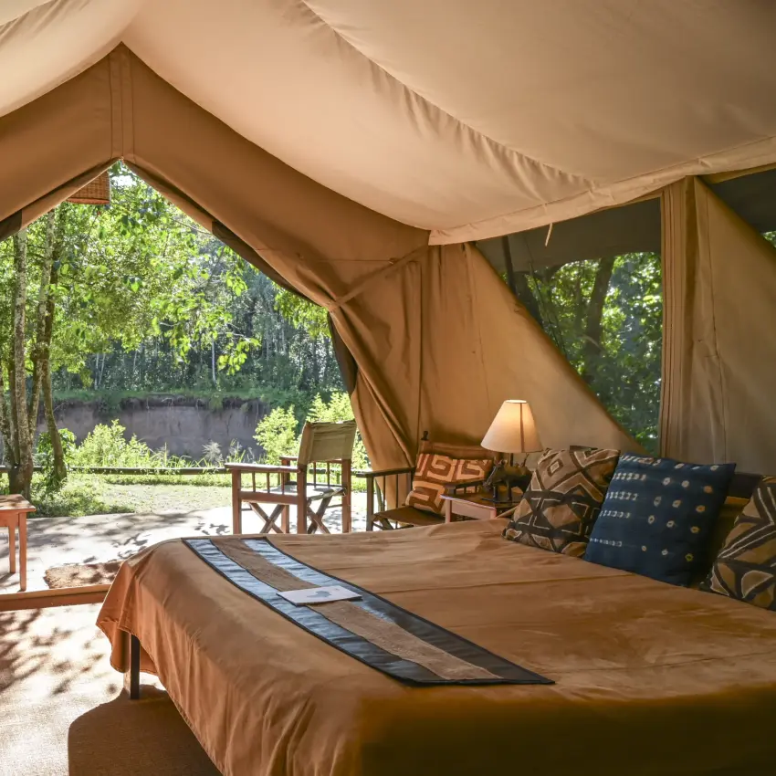 Luxury safari tent interior with beds overlooking river and woodland, Governors’ Camp, Maasai Mara, Kenya