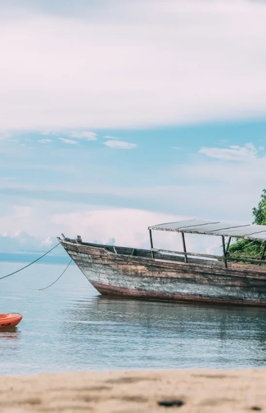 Fisherman with boat and orange buoys on tropical water, Mahale Mountains, Tanzania