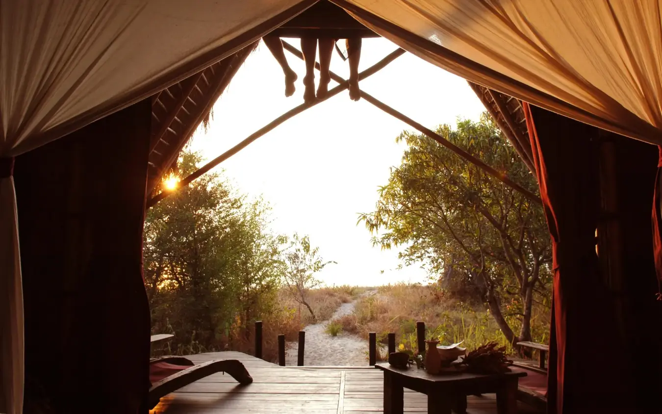 Wooden deck with draped curtains overlooking river at sunset, Greystoke Mahale, Mahale Mountains, Tanzania