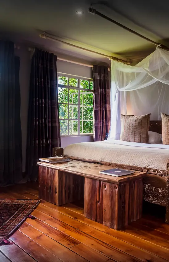 Luxury bedroom with canopy bed and large windows overlooking forest, Hemingways Eden Residence, Nairobi, Kenya