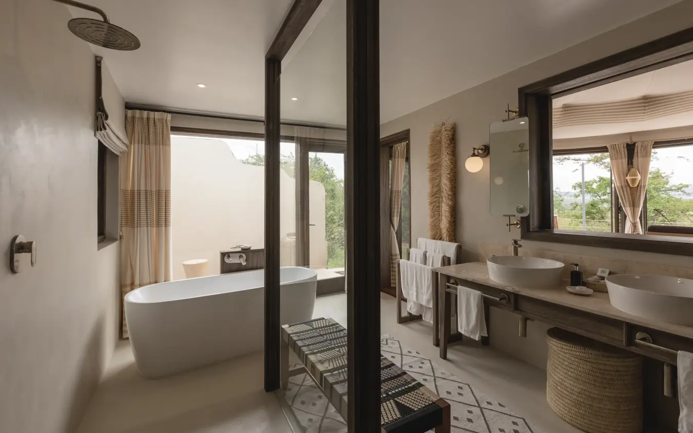 Luxury bathroom with freestanding tub and glass partition overlooking landscape, Hemingways Ol Seki Mara, Maasai Mara, Kenya