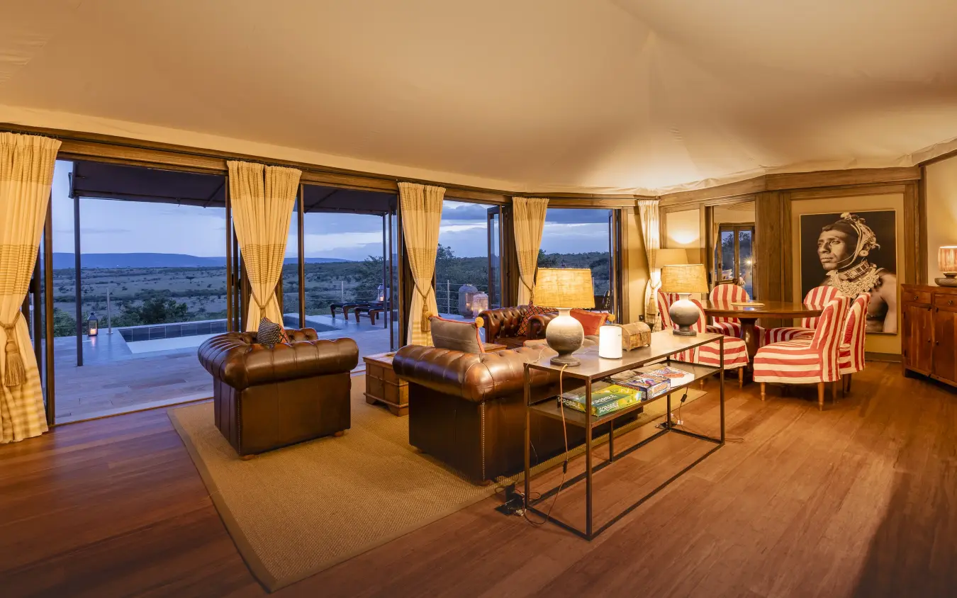 Luxury lodge suite with leather furniture overlooking vast savanna landscape at dusk, Hemingways Ol Seki Mara, Maasai Mara, Kenya