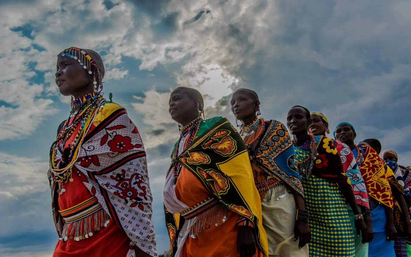Group of women in traditional beaded clothing standing against cloudy sky, Hemingways Ol Seki Mara, Maasai Mara, Kenya