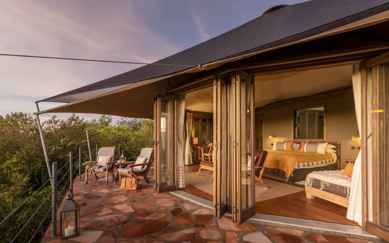 Luxury bedroom suite with open-air deck overlooking woodland savanna at dusk, Hemingways Ol Seki Mara, Maasai Mara, Kenya