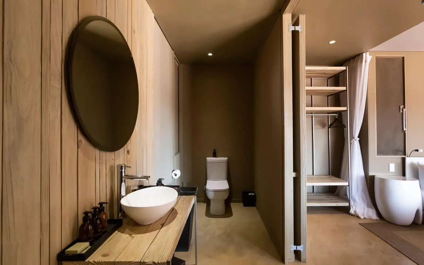 Modern bathroom with round mirror and wooden vanity, Hoanib Skeleton Coast Camp, Skeleton Coast, Namibia