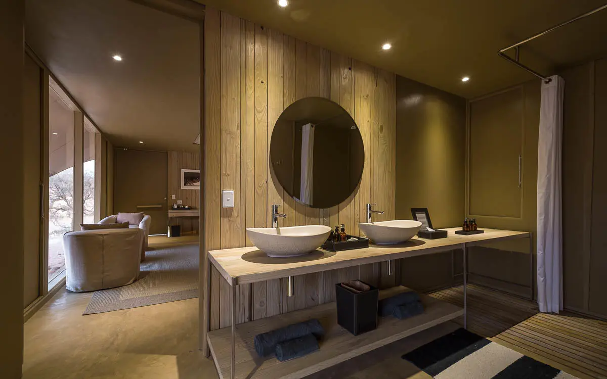 Luxury bathroom with dual vessel sinks and round mirror, Hoanib Skeleton Coast Camp, Skeleton Coast, Namibia