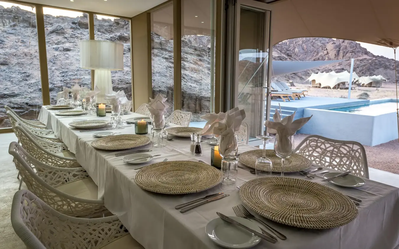 Elegant dining room with table settings overlooking pool, Hoanib Skeleton Coast Camp, Skeleton Coast, Namibia