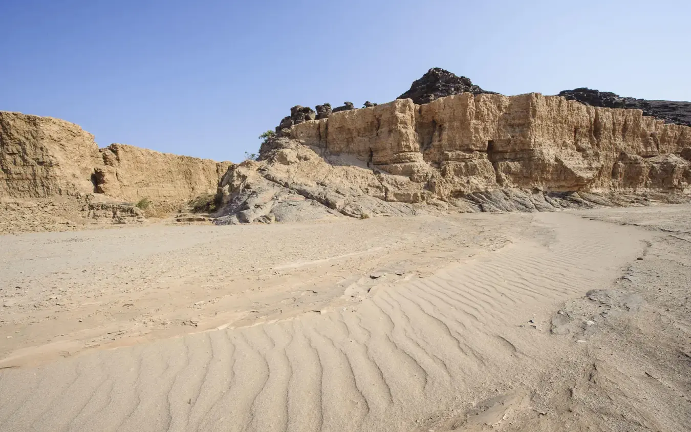 Desert coastline with layered rock formations and sand patterns, Hoanib Skeleton Coast Camp, Skeleton Coast, Namibia