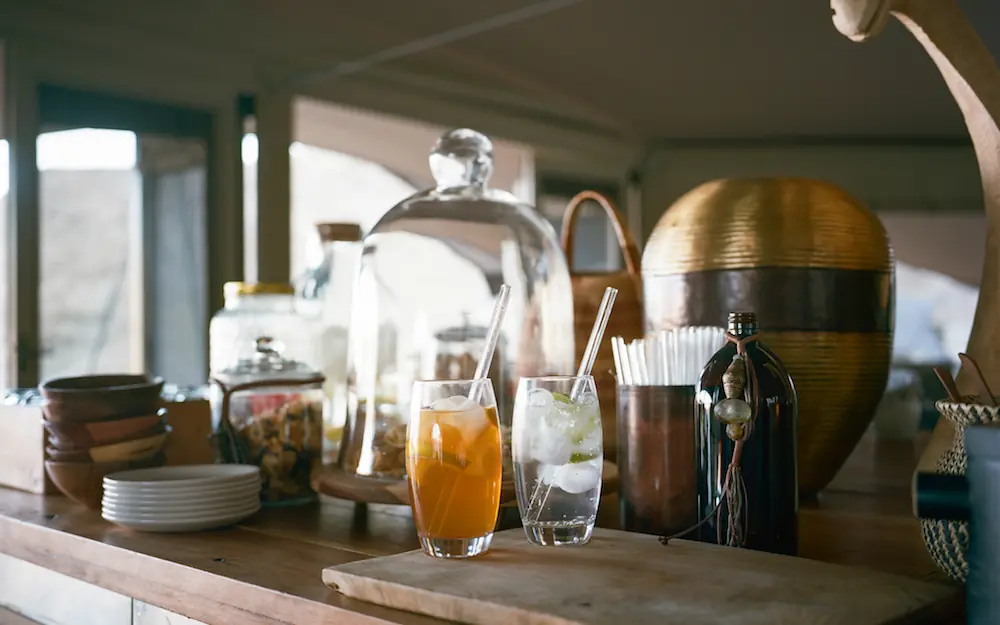Bar counter with beverages and glassware in lodge interior, Hoanib Valley Camp, Damaraland, Namibia