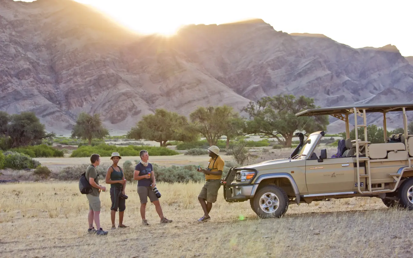 Guide leading walking safari group through desert landscape, Hoanib Valley Camp, Damaraland, Namibia