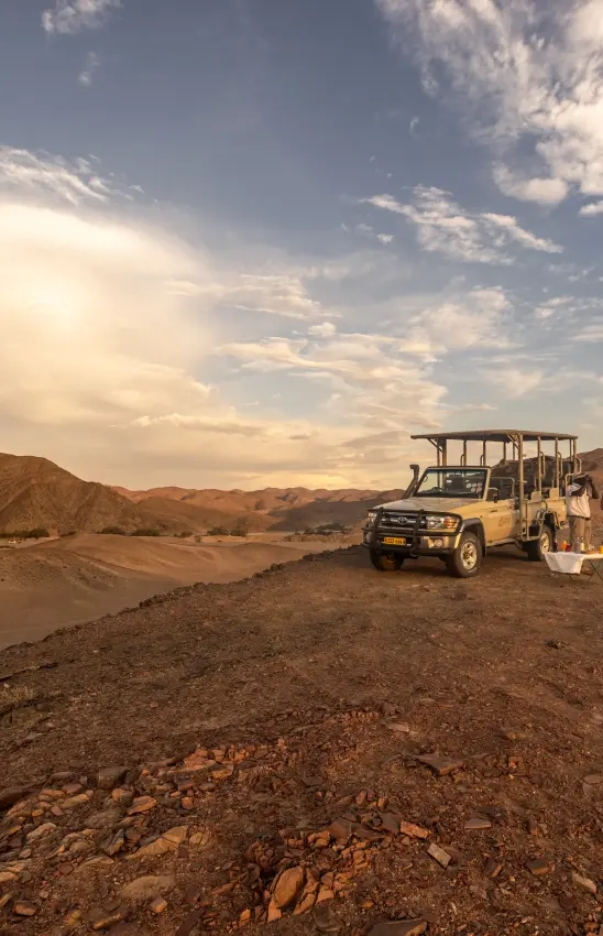 Open-sided safari vehicle with passengers in desert landscape, Skeleton Coast, Namibia