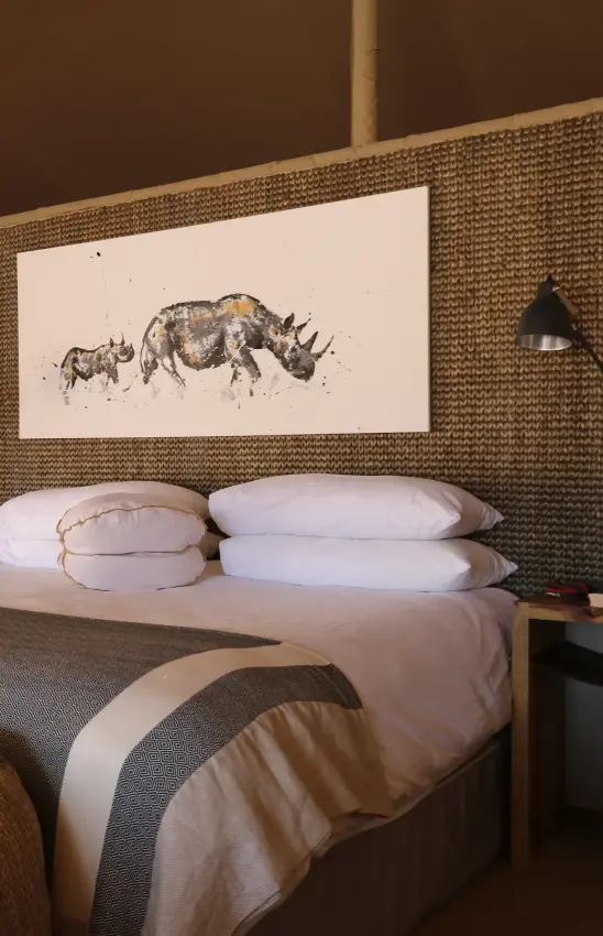 Bedroom with brick accent wall and wildlife artwork, Hoanib Valley Camp, Damaraland, Namibia