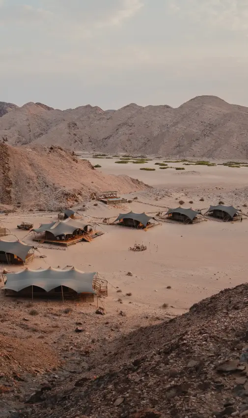 Camp tents and structures scattered across desert valley floor, Hoanib Valley Camp, Skeleton Coast, Namibia