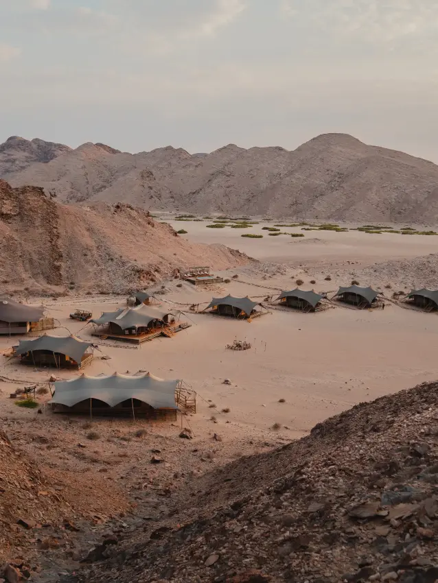 Camp tents and structures scattered across desert valley floor, Hoanib Valley Camp, Damaraland, Namibia