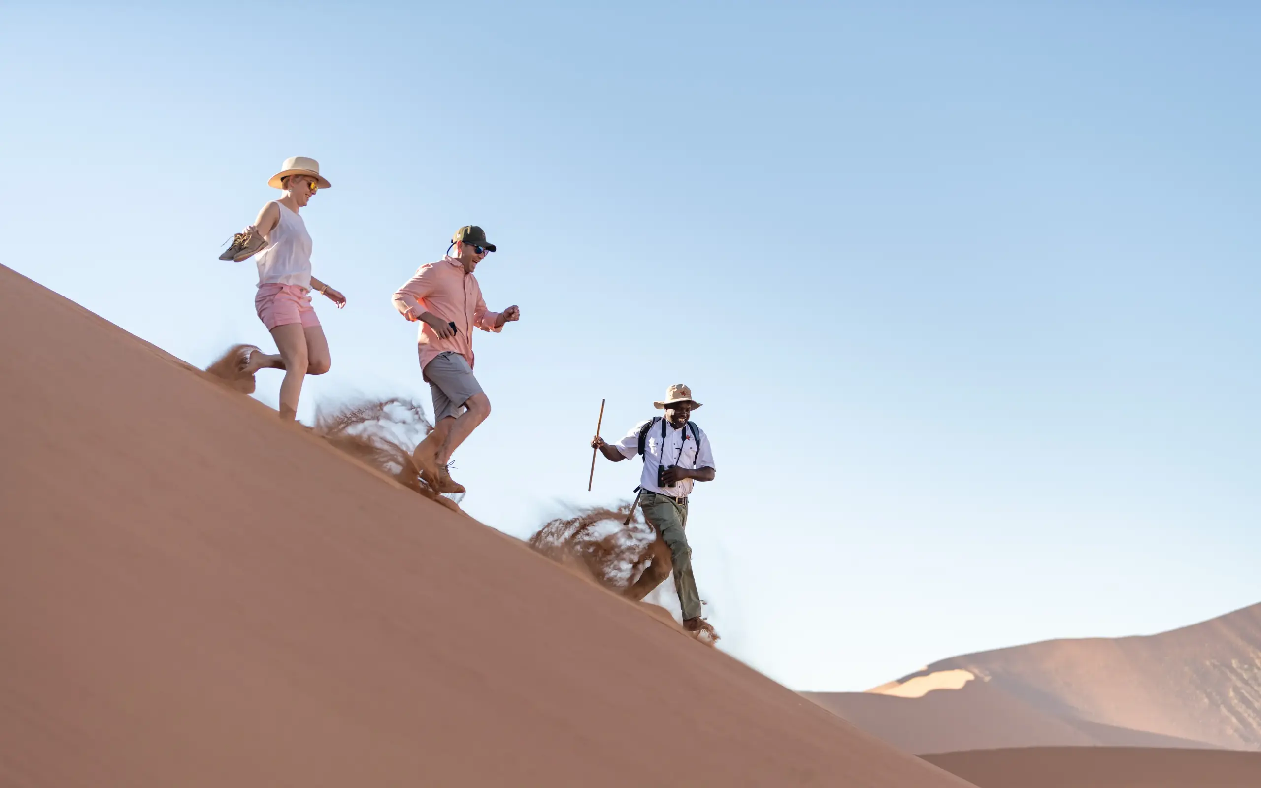 Guests hiking down a large sand dune in desert, Hoodia Desert Lodge, Sossusvlei, Namibia
