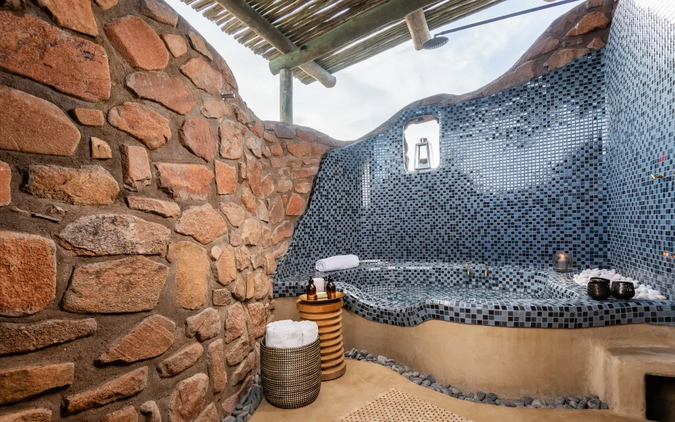 Open-air bathroom with stone walls and tiled soaking tub, Hoodia Desert Lodge, Sossusvlei, Namibia